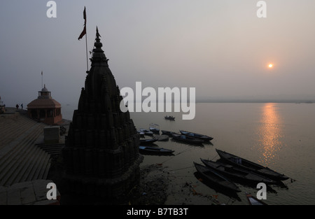 Die Sonne geht über dem Fluss Ganges bei Scindia Ghat in Varanasi. Stockfoto