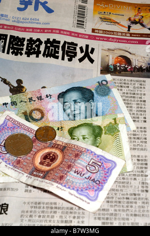 China-Banknoten und-Münzen sowie Zeitung Stockfoto