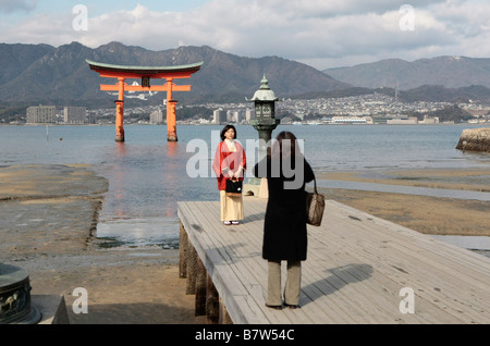 Ein japanischer Tourist hat ihr Foto vor dem Tor Torii am Itsukushima-Schrein auf der Insel Miyajima, Japan. Stockfoto