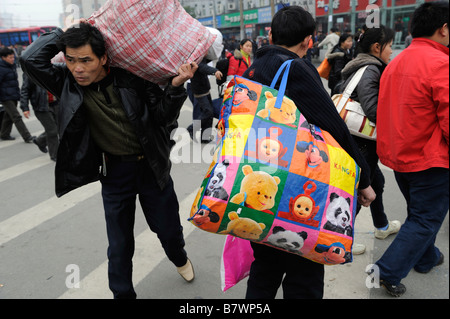 Migrantische ArbeiterInnen tragen ihr Gepäck verlassen den Bahnhof von Nanchang, Jiangxi, China. 5. Februar 2009 Stockfoto