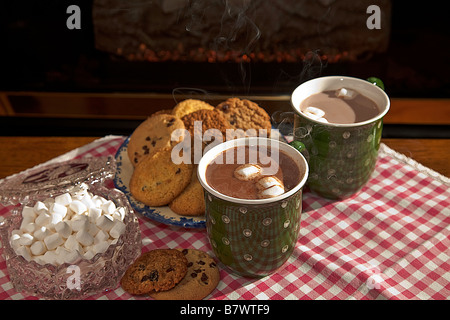 Eine Tasse heiße dampfende Schokolade oder Kakao mit Cookies durch einen Kamin Stockfoto
