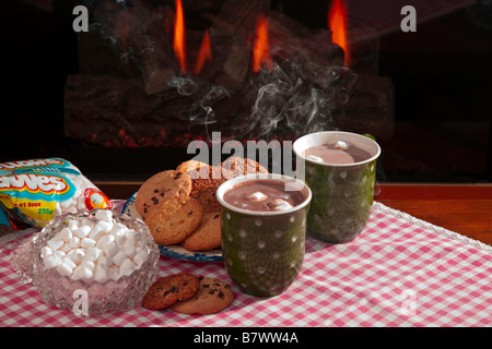 Eine Tasse heiße dampfende Schokolade oder Kakao mit Cookies durch einen Kamin Stockfoto