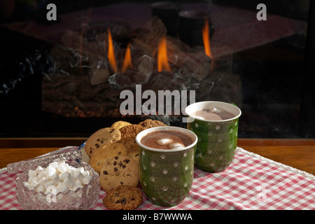 Eine Tasse heiße dampfende Schokolade oder Kakao mit Cookies durch einen Kamin Stockfoto