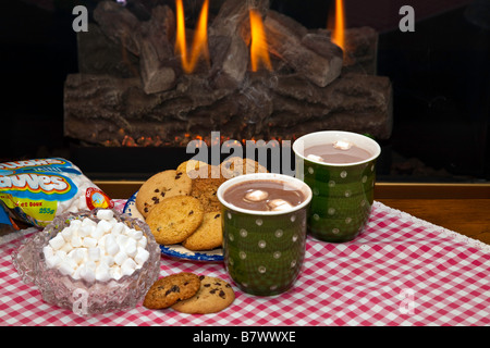 Eine Tasse heiße dampfende Schokolade oder Kakao mit Cookies durch einen Kamin Stockfoto
