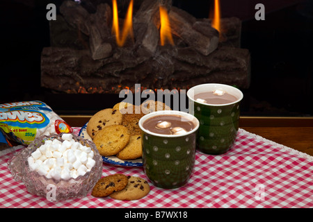 Eine Tasse heiße dampfende Schokolade oder Kakao mit Cookies durch einen Kamin Stockfoto