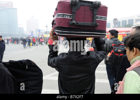 Migrantische ArbeiterInnen tragen ihr Gepäck vom Bahnhof in Nanchang, Jiangxi, China zu verlassen. 5. Februar 2009 Stockfoto