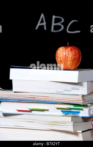 Ein Apfel auf einem Stapel Bücher auf dem Lehrer-Schreibtisch Stockfoto