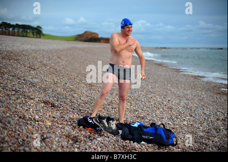 Ein Mann bereitet sich auf das Tragen einer Badekappe schwimmen gehen und am Strand von Budleigh Salterton Schutzbrillen. Stockfoto