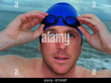 Ein Mann bereitet sich auf Meer schwimmen eine Badekappe tragen gehen und am Strand von Budleigh Salterton Schutzbrillen. Stockfoto