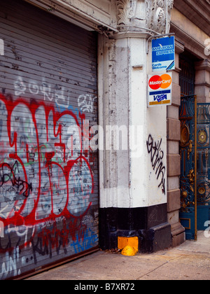 Gängigen Kreditkarten-Logos auf einem Schild angebracht, um eine Betonstütze neben Stahl Sicherheitstüren in Graffiti bedeckt. Stockfoto