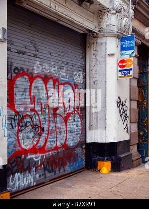 Gängigen Kreditkarten-Logos auf einem Schild angebracht, um eine Betonstütze neben Stahl Sicherheitstüren in Graffiti bedeckt. Stockfoto