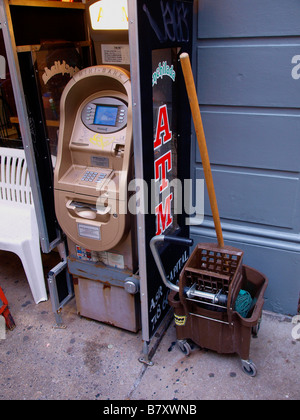 Ein Geldautomat, mop und mop Eimer vor einem Café auf einem New Yorker Bürgersteig in Greenwich Village. Stockfoto