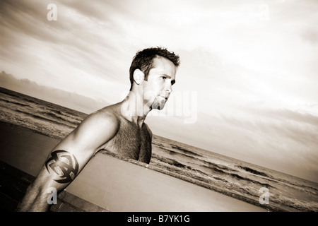 Surfer am Strand holding Surfbrett Wandern, Porträt Stockfoto