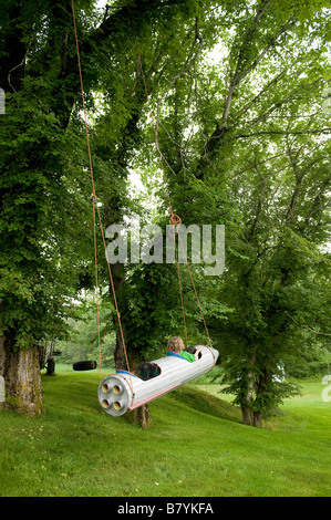 Kleiner Junge fliegt um in einem Raumschiff an einem Baum hängen. Stockfoto