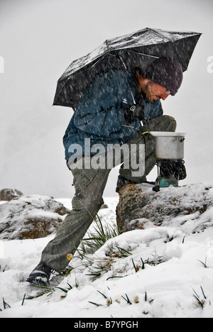 Mann mit Regenschirm versucht, nach einem schweren Schnee Kochen fallen Ala Kol See Kirgisistan Stockfoto