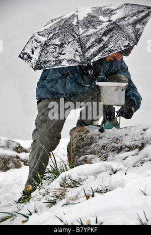 Mann mit Regenschirm versucht, nach einem schweren Schnee Kochen fallen Ala Kol See Kirgisistan Stockfoto