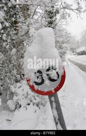 Schnee bedeckt 30mph Warnschild auf einer Landstraße Stockfoto