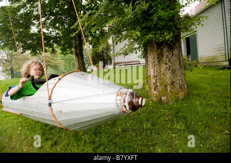 Kleiner Junge fliegt um in einem Raumschiff an einem Baum hängen. Stockfoto