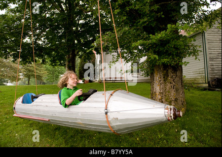 Kleiner Junge fliegt um in einem Raumschiff an einem Baum hängen. Stockfoto