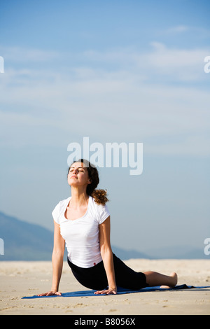 Junge Frau beim Yoga am Strand Stockfoto