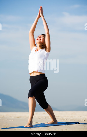 Junge Frau beim Yoga am Strand Stockfoto