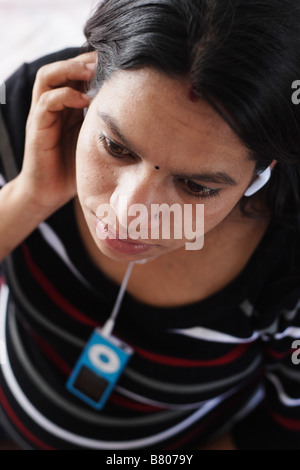 Asiatische Hindu-Frau anhören von Musik von einem iPod Stockfoto