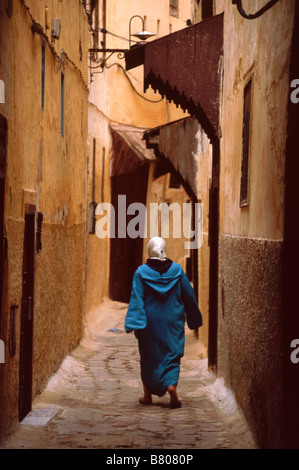 Frau trägt traditionelle marokkanische Jellabah Spaziergänge entlang der schmalen Gasse in der Medina von Meknès, Marokko, Nord Affrica Stockfoto