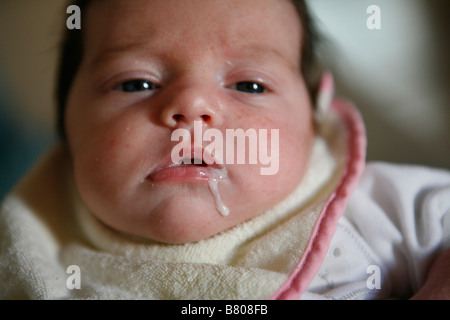 Ein Baby tropft Milch aus ihrem Mund Stockfoto