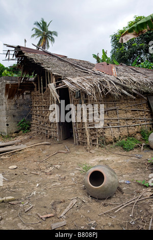 Einen alten Tontopf sitzt auf dem Boden vor einer unvollständigen Flechtwerk und Lehm-Haus in einem abgelegenen stürmischen Dschungel Dorf von Nigeria Stockfoto