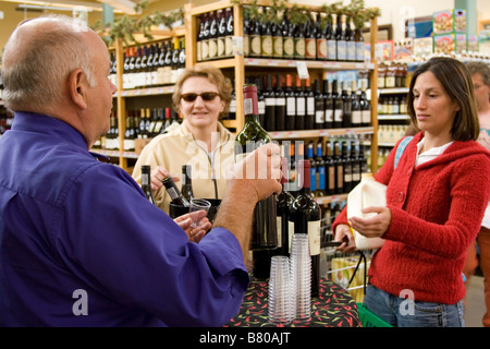 Man bietet kostenlose Proben von Wein mit zwei Frauen im Supermarkt Stockfoto