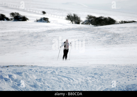 Ein Langläufer macht ihren Weg über den South Downs Way auf Ditchling Leuchtfeuer im Schnee UK Stockfoto