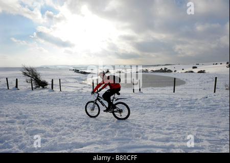 Ein unerschrockener Radfahrer kämpft sich durch den Schnee auf Ditchling Leuchtfeuer in Sussex UK Stockfoto