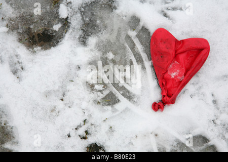 Roten herzförmigen Luftballon in den Schnee getrampelt. Stockfoto