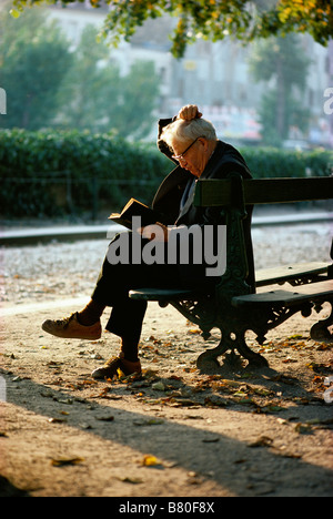Älterer Mann ein Leder gebundenes Buch zu lesen, an einem Herbsttag auf einer Parkbank in Paris, Frankreich Stockfoto