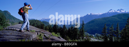 Ein Wanderer, der Blick durch ein Fernglas auf den Blick der Tantalus Mountain Range in der Nähe von Whistler und Squamish British Columbia Kanada Stockfoto