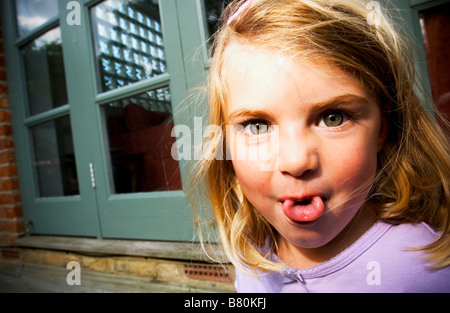 kleine Mädchen ihre Zunge machen ein lustiges Gesicht Stockfoto