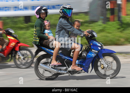 Motorrad mit eine Frau trägt einen Helm und vier Kinder ohne Helm in Biak, Indonesien. Stockfoto