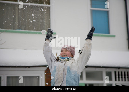 12 Jahre altes Mädchen in Wollmütze wirft Schnee in die Luft tagsüber außerhalb der Schule im verschneiten Wetter 2009 Stockfoto