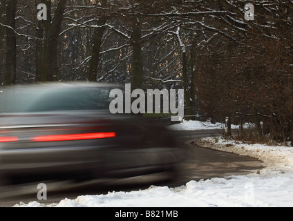 Schnelle Auto Beschleunigung rund Kurve auf eisigen, verschneiten, schneebedeckten Straße durch Wald im Winter Stockfoto