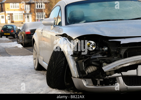 Stock Foto von einem abgestürzten Auto zeigt die Schäden an seinen Frontflügel das Auto geparkt war am Straßenrand im verschneiten Wetter Stockfoto