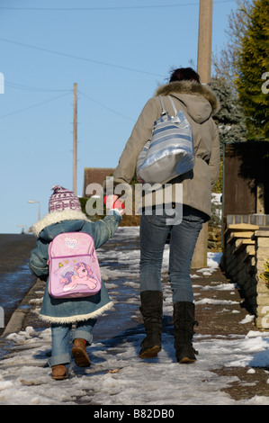 Stock Foto einer Frau und Kind gehen Hand in Hand im Schnee bergauf Stockfoto