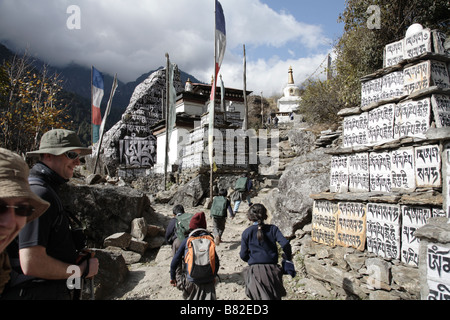 Kinder laufen vorbei an Wanderer und Gebet Steinen in Nepal auf einem Pfad Stockfoto