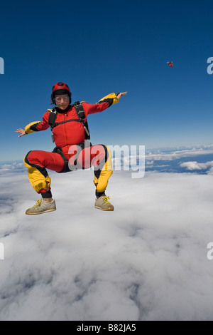 Fallschirmspringer ist sitzen über eine große Wolke am blauen Himmel fliegen und dabei Spaß haben. Die Uferlinie auf der Rückseite ist als Referenz zu tauchen. Stockfoto