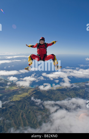 Fallschirmspringer ist sitzen über eine große Wolke am blauen Himmel fliegen und dabei Spaß haben. Die Uferlinie auf der Rückseite ist als Referenz zu tauchen. Stockfoto