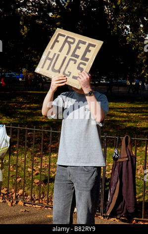 Ein Mann mit seinem Gesicht verdeckt durch ein Free Hugs Zeichen Stockfoto