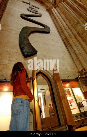 Eine junge Frau, die nach oben auf eine Kreuz-Symbol an der Wand der Ely Cathedral Stockfoto