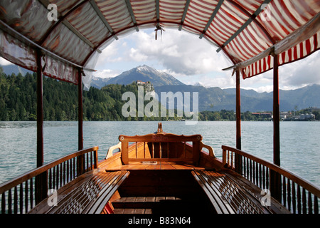 Ein Blick auf die Burg von Bled (Blejski Grad) durch die Baumkronen des eine Gondel vertäut am Bleder See-Ufer in Gorenjska, Slowenien Stockfoto