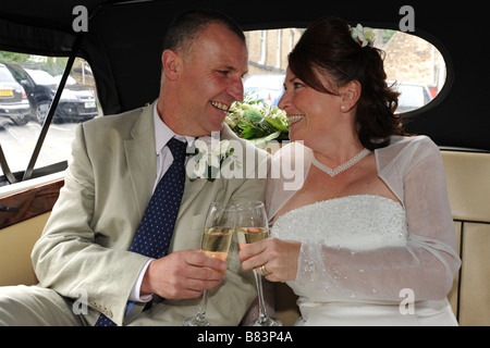 Frisch vermählte Paar Toasten mit Champagner in ihrem Auto, North Yorkshire Modell veröffentlicht Stockfoto