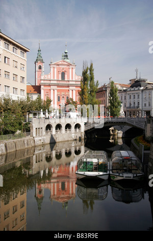 Tour Boote vertäut am Ufer des Flusses Ljubljanica mit dreifach-Brücke hinter sich, in die Hauptstadt Ljubljana, Slowenien Stockfoto