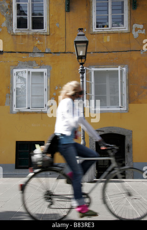 Ein Radfahrer fährt durch die Altstadt entlang einem Pfad neben dem Fluss Ljubljanica in der Hauptstadt Ljubljana, Slowenien Stockfoto